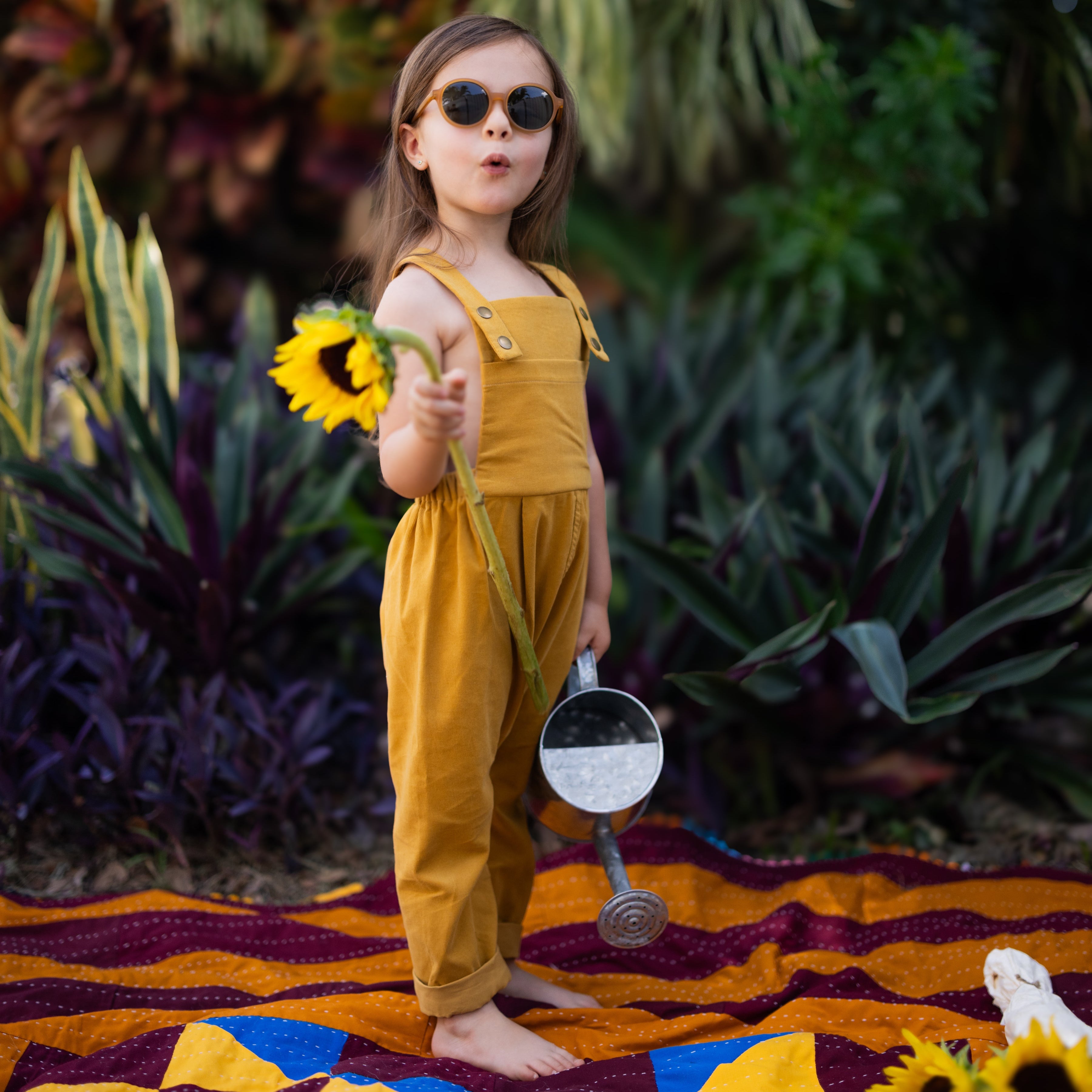 Close-up of the 4-year-old girl in ginger long overalls, displaying the adjustable straps and elegant pleats that add sophistication to the overall look.