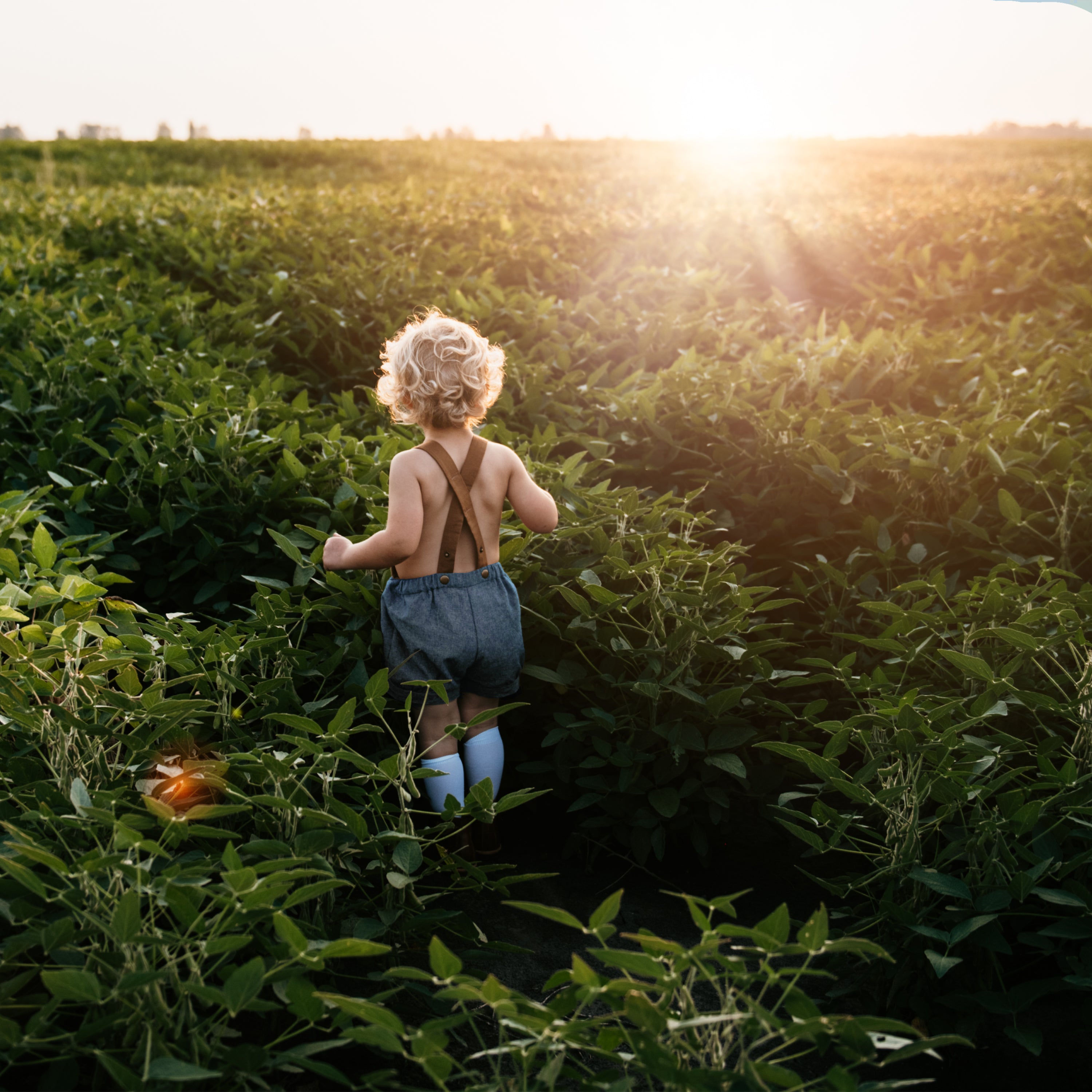 Close-up of the back details of chambray blue linen short overalls, featuring unique leather-looking linen/cotton straps, emphasizing the original design and quality craftsmanship.