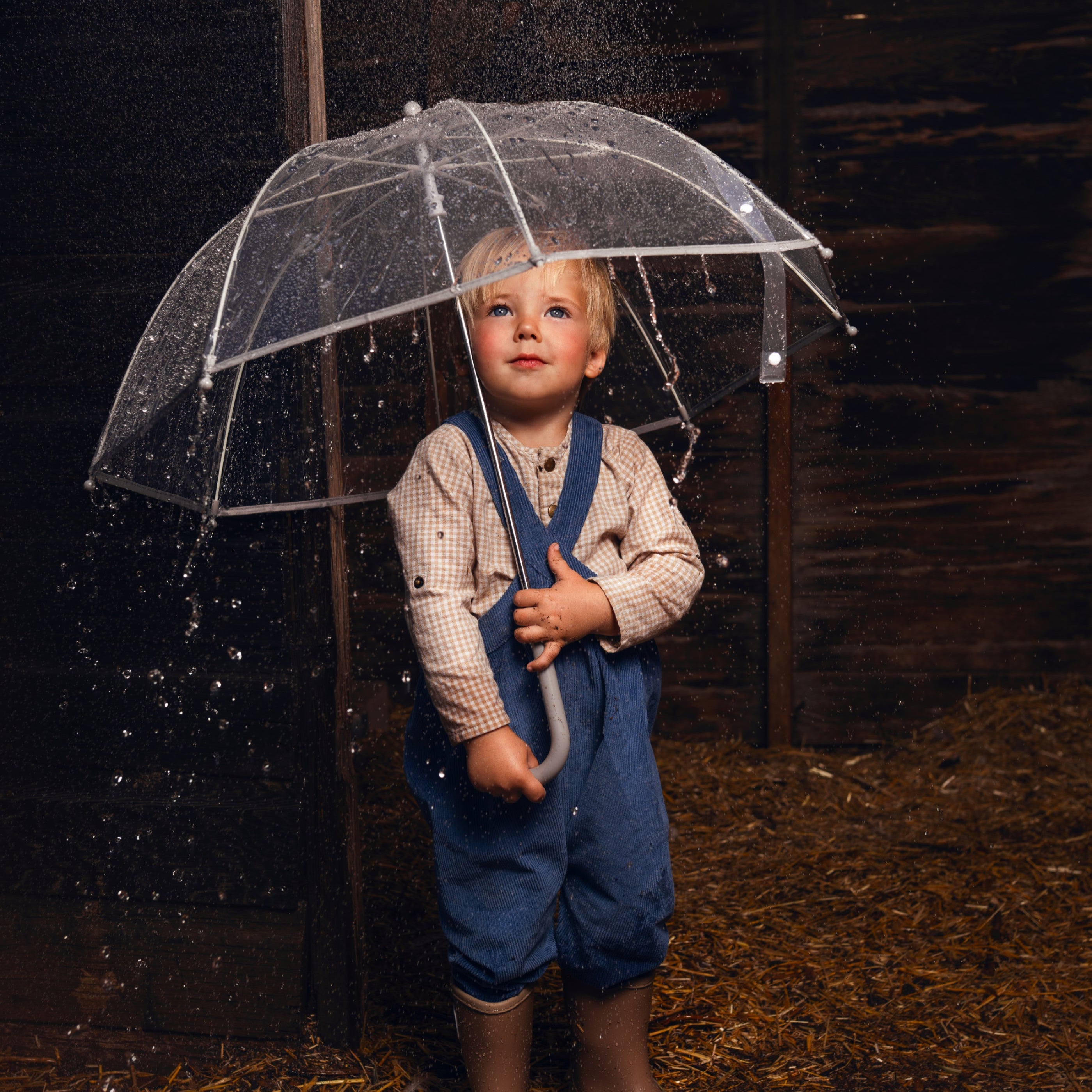 Child holding a transparent umbrella in a dark setting