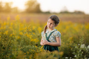 Young girl standing in a field of yellow flowers with a blurred background