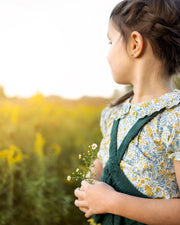 girl holding flowers in a field with a blurred background