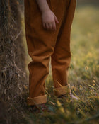 Girl wearing brown pants standing in a grassy field with a blurred background