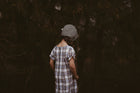 Girl in a plaid dress and green bonnet from the back