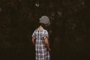 Girl in a plaid dress and green bonnet from the back