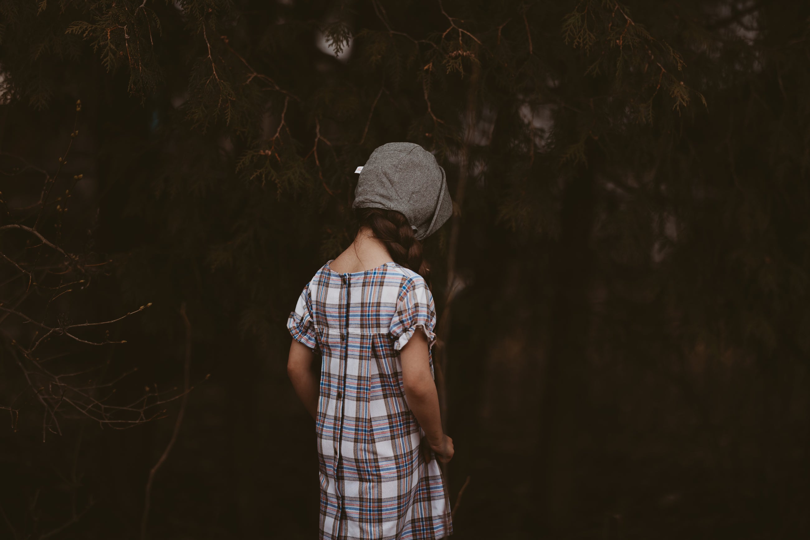 Girl in a plaid dress and green bonnet from the back