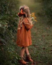 Model girl showcasing the back view with a playful pose - This photo captures the model in a fun pose, highlighting the dress’s playful ruffled sleeves and its stylish silhouette.