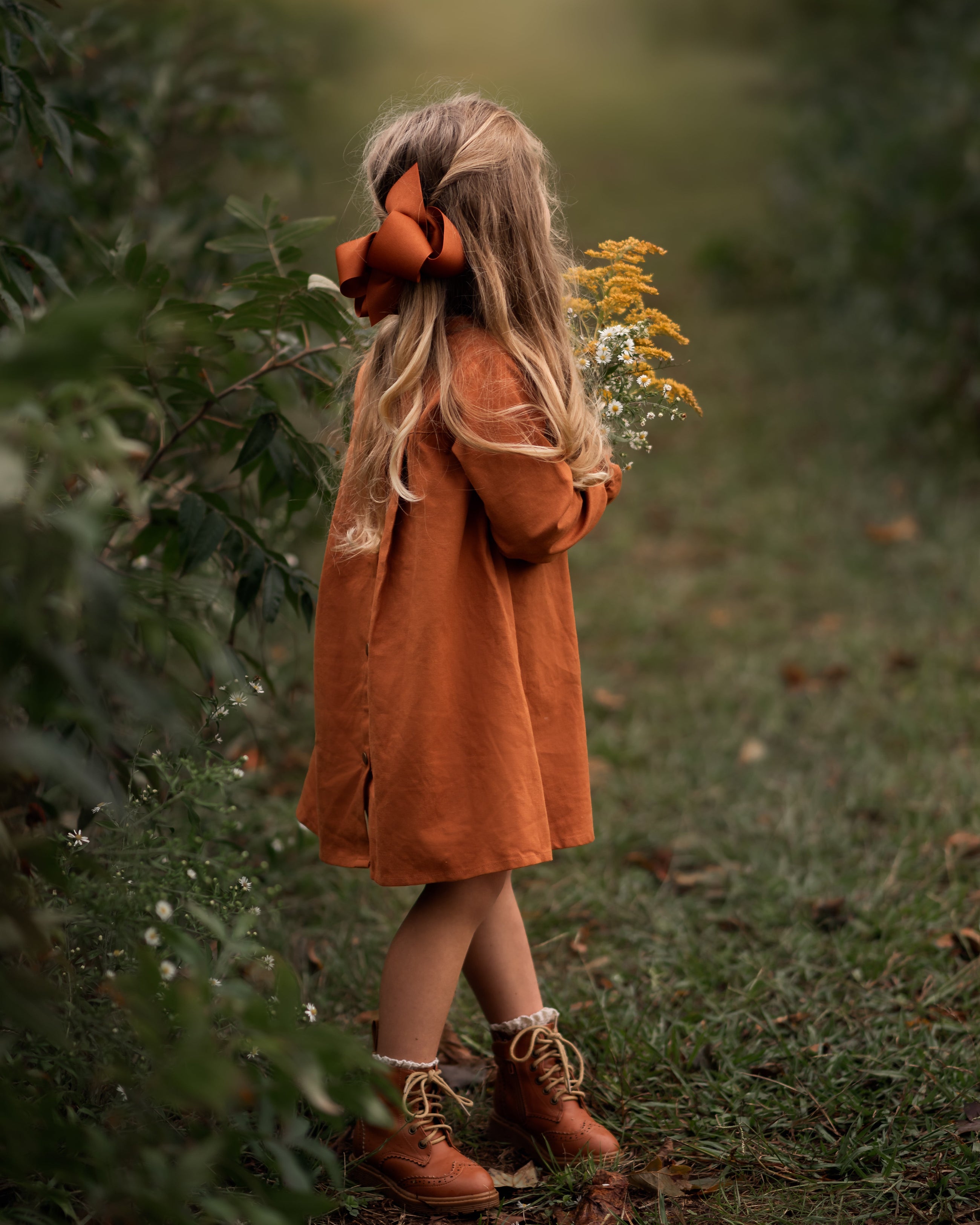 Model girl showcasing the back view with a playful pose - This photo captures the model in a fun pose, highlighting the dress’s playful ruffled sleeves and its stylish silhouette.