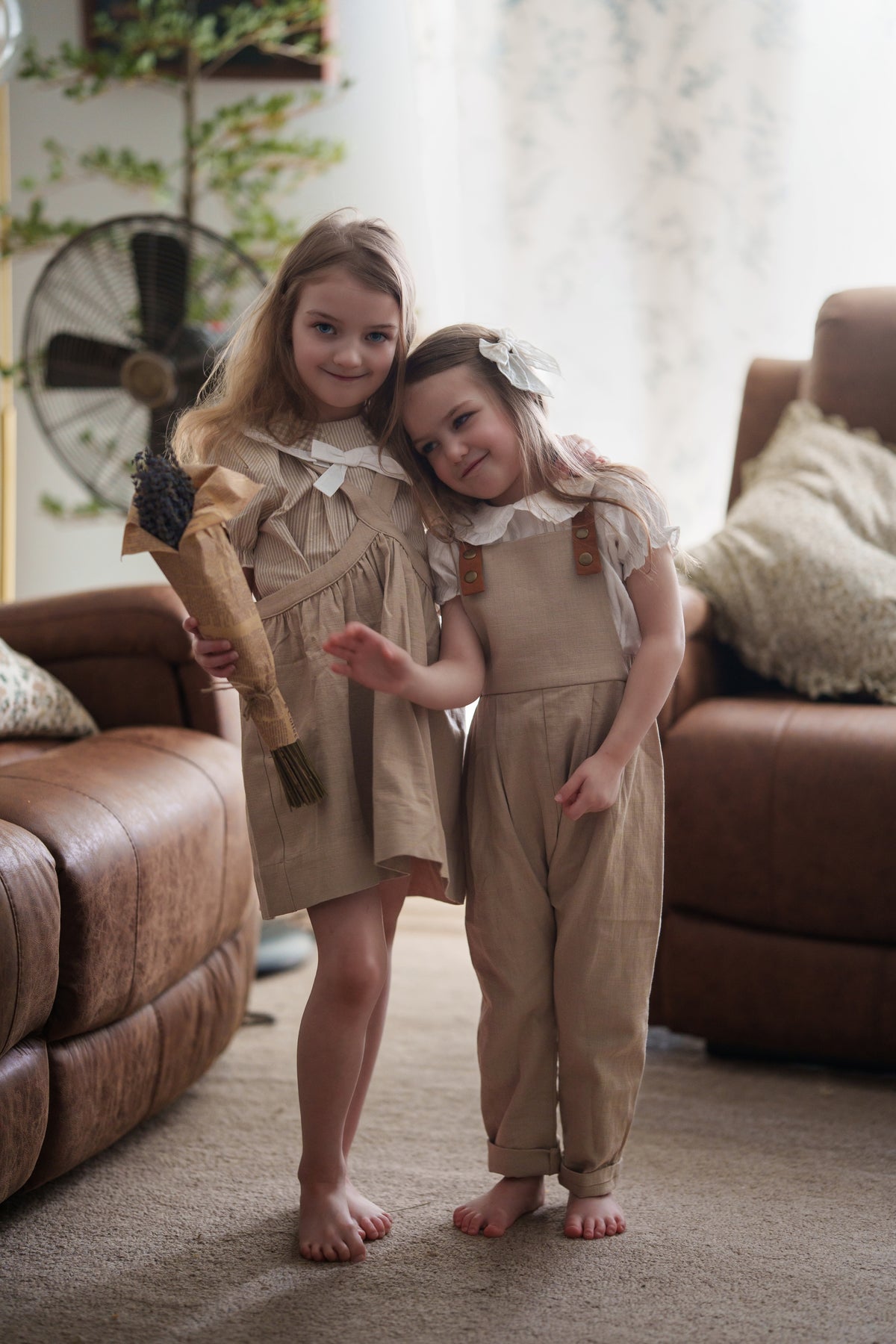 Two young girls in matching outfits standing in a living room.