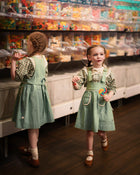 Two young girls in matching outfits standing in a candy store.