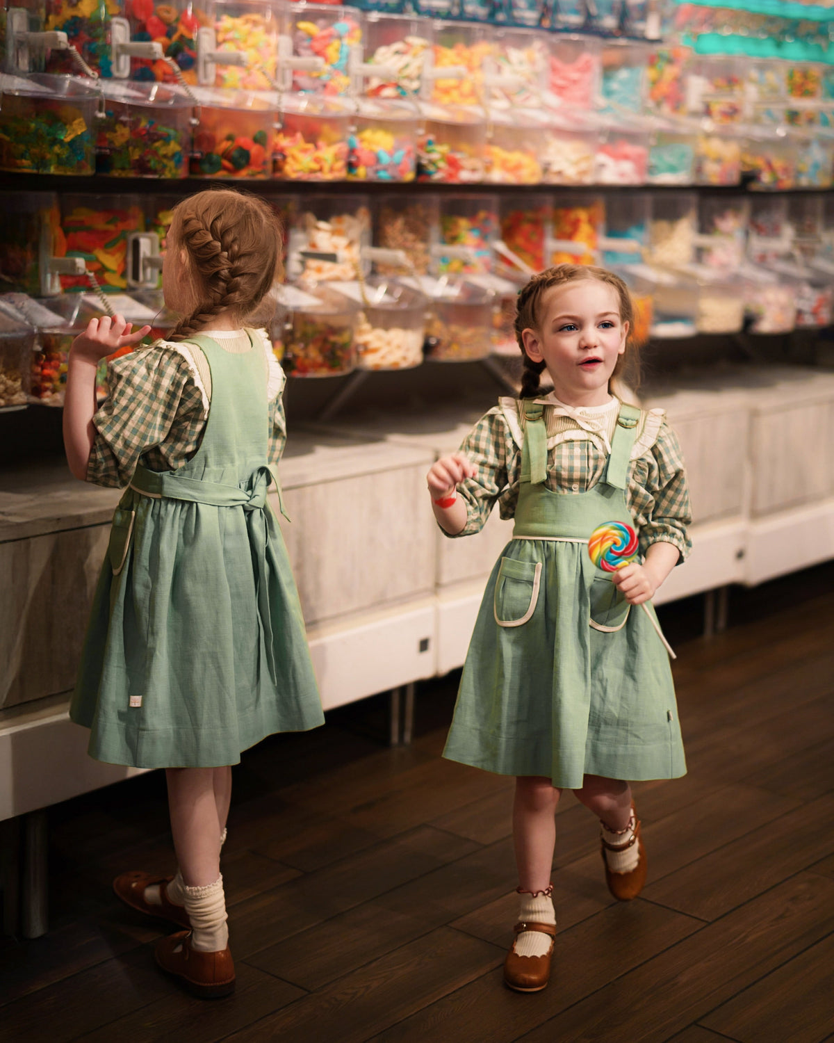 Two young girls in matching outfits standing in a candy store.