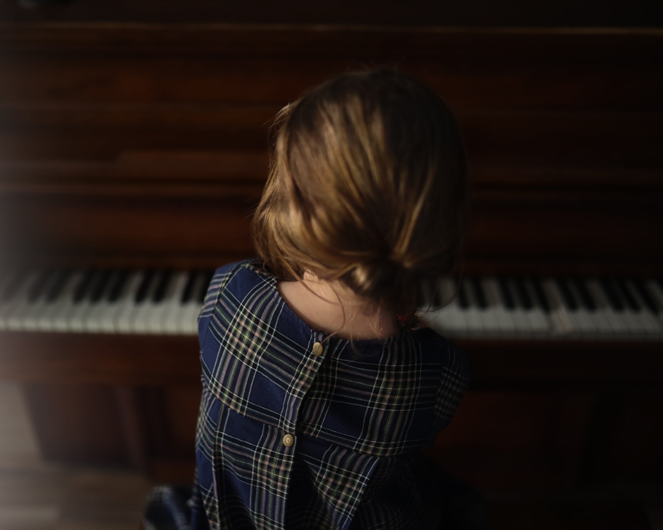 Person sitting in front of a piano with a dark, moody atmosphere