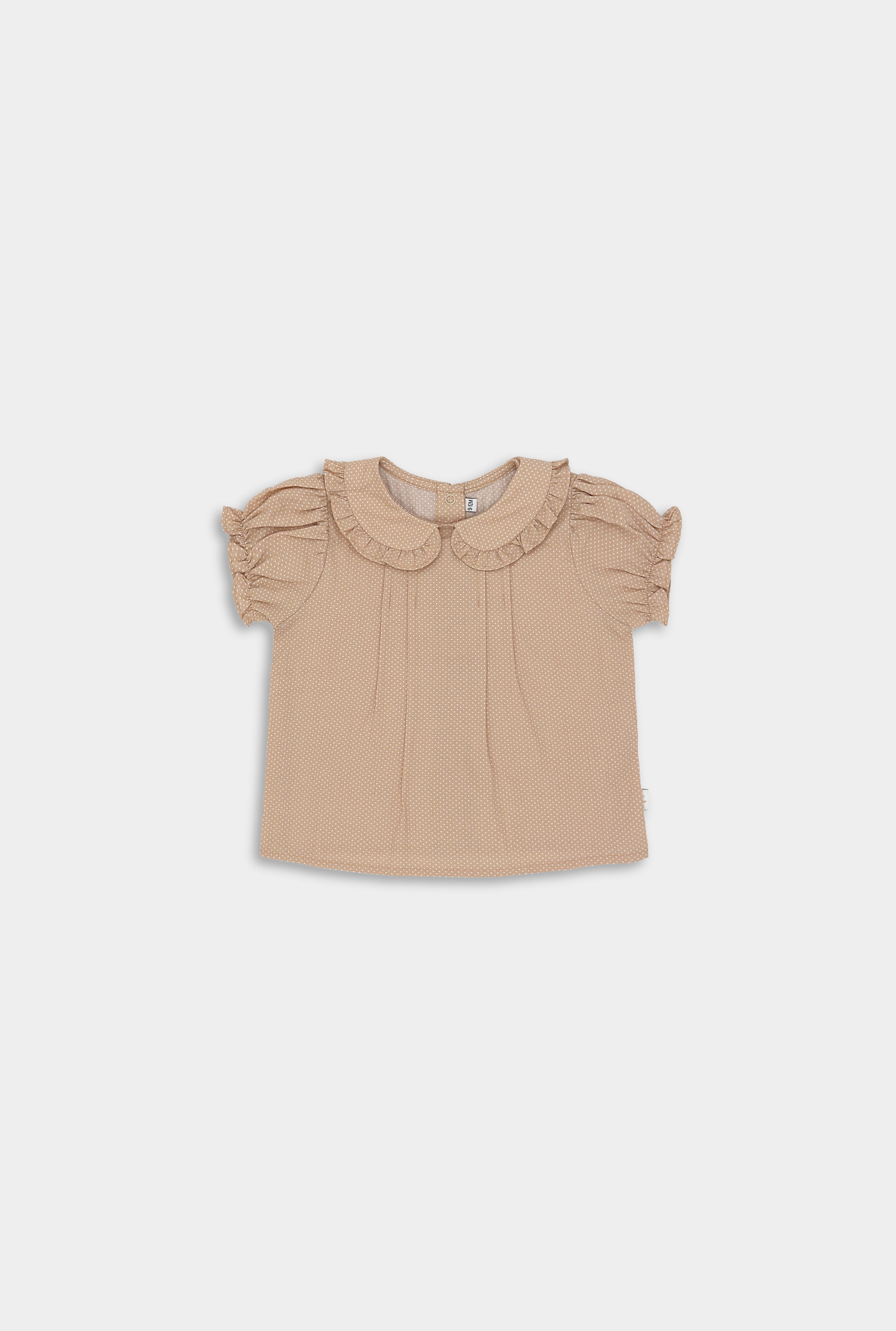 Front of beige blouse with white Swiss dots featuring a Peter Pan collar adorned with ruffles, short puffy sleeves with ruffled hems, and a snap closure at the back. Available in sizes 9-12 months to 5 years, made from natural pre-washed cotton for comfort.