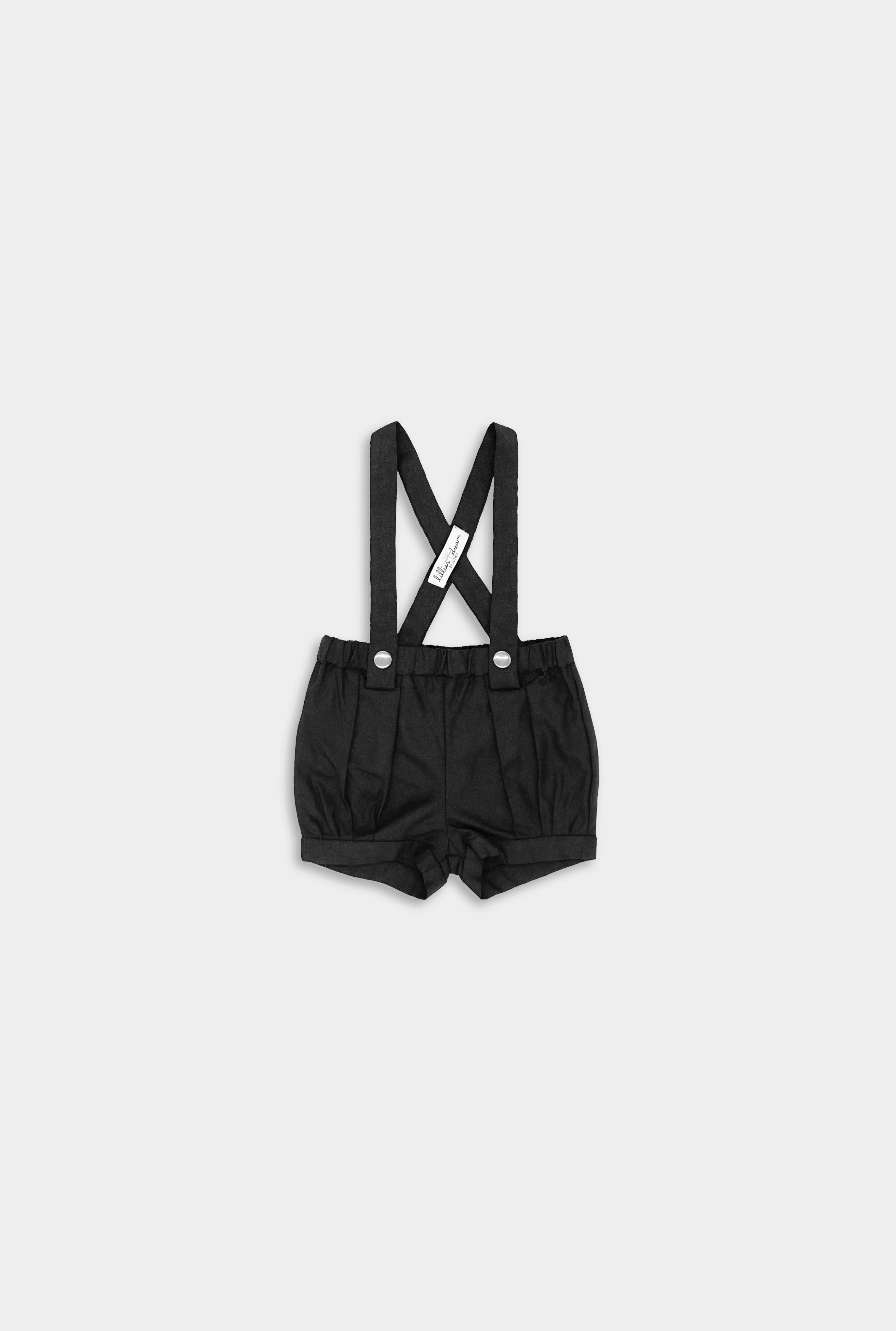 Front view for A pair of black linen suspender shorts for boys featuring adjustable straps for a customized fit, stylish pleats and cuffs for added sophistication, a conveniently positioned label to keep straps up, and versatile strap options with six lengths for flexible styling, allowing them to be worn crossed or straight.