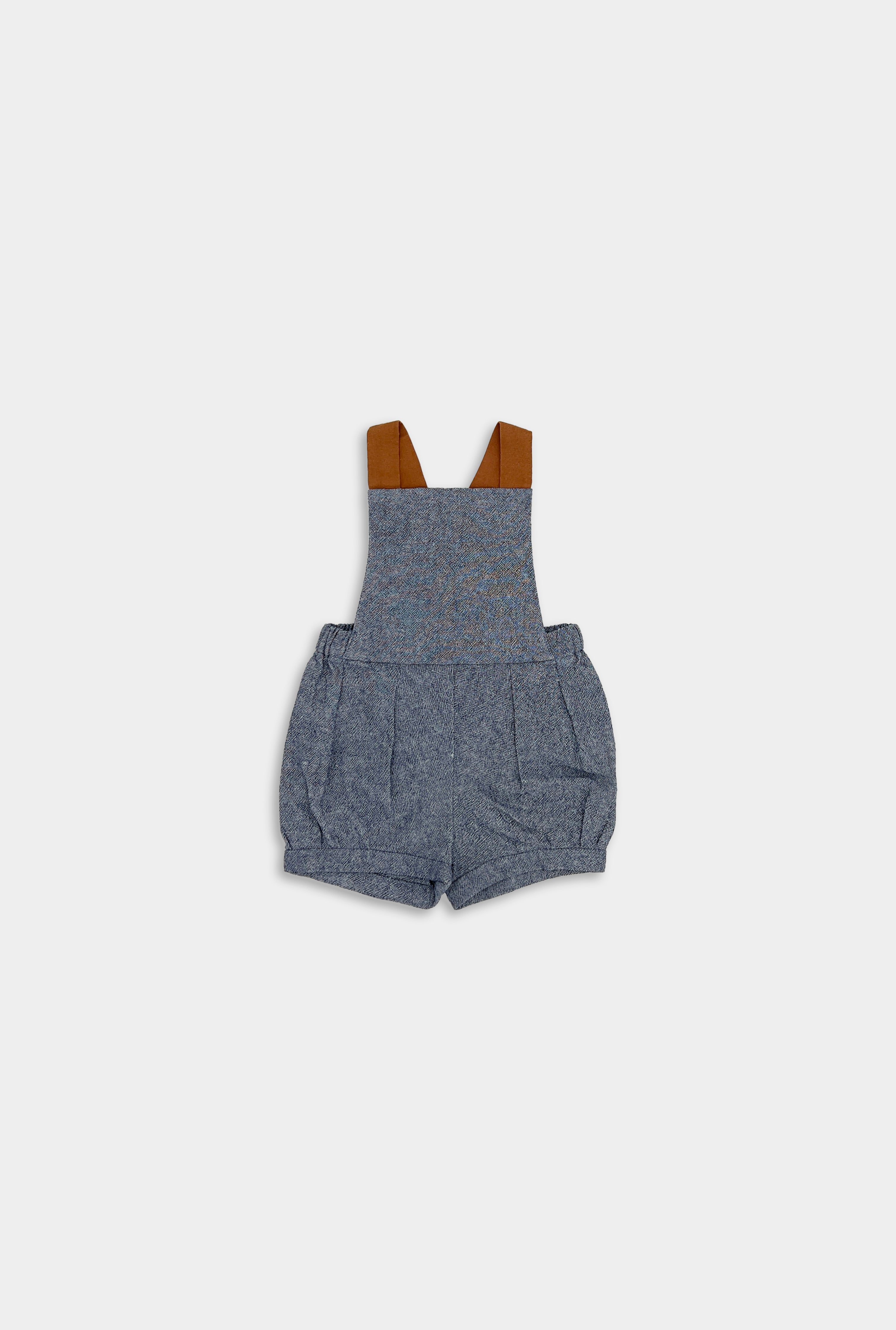 Front view of stylish chambray blue linen short overalls, showcasing elegant pleats and cuffs, emphasizing high-quality craftsmanship for children’s wear.