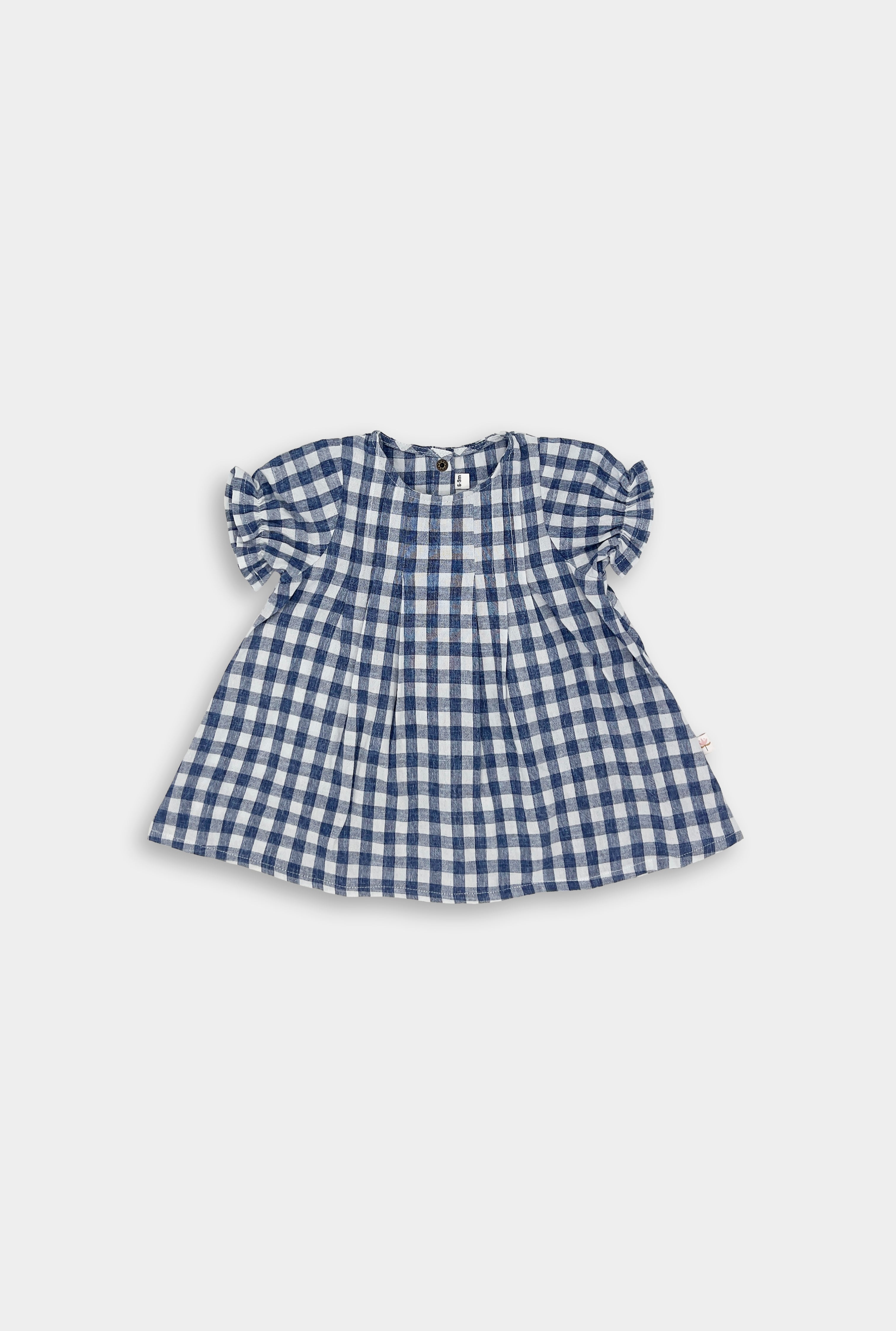 A full view of a Blue Gingham linen dress, showcasing its beautiful design with a pin-tucked front and a yoke featuring two pleats at the back. The dress has delicate ruffles at the short sleeve hem and an A-line shape, perfect for warm summer days. Pre-washed to ensure it retains its shape and minimizes shrinking, this dress embodies a charming and practical style for little girls.
