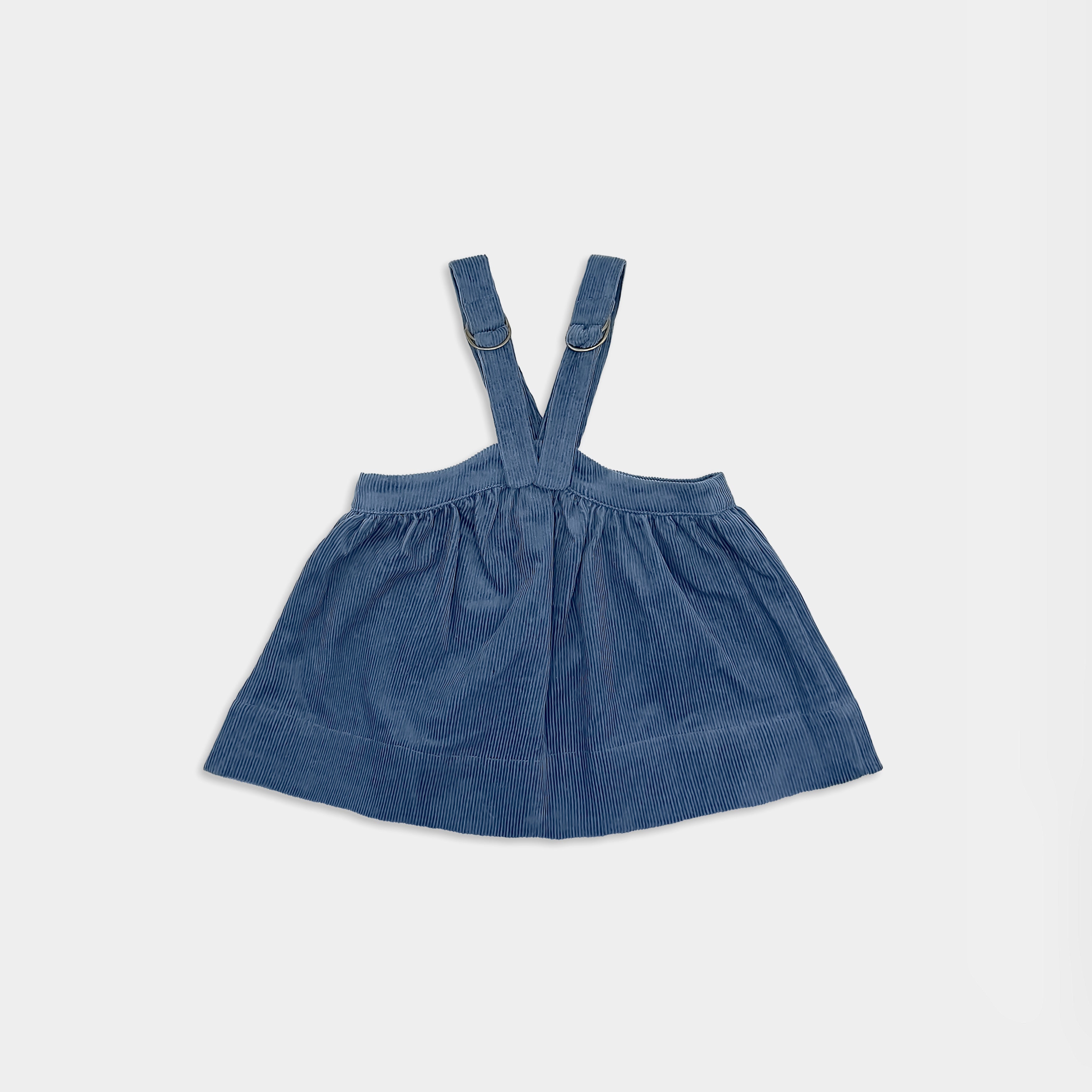 Back view of blue corduroy dress for small girls with suspenders on a light grey  background