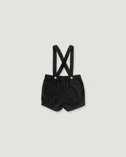 Black baby boy's shorts with adjustable shoulder straps and silver snap buttons, laid flat on a light gray background.