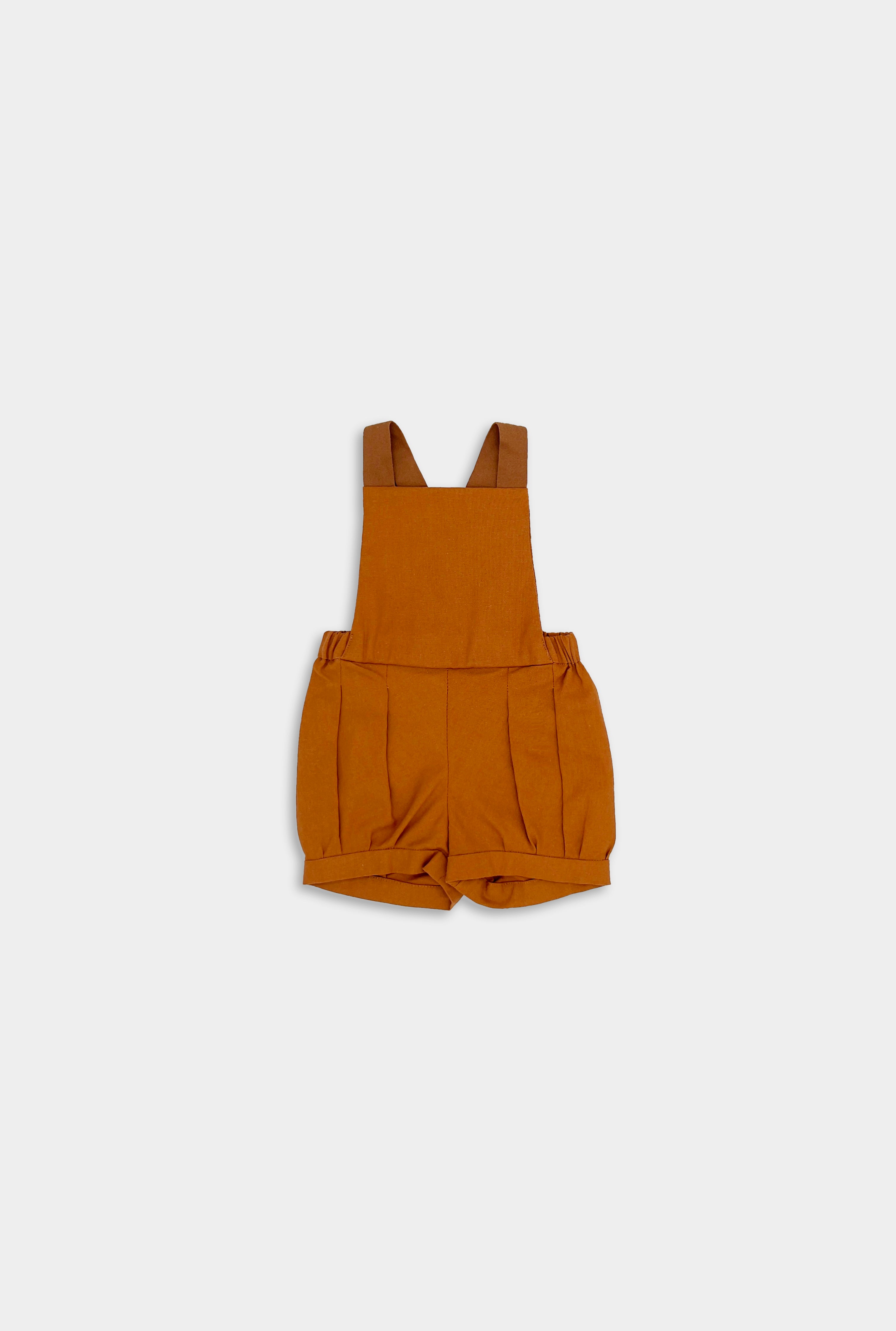 Photo of the Burnt Orange Short Overalls alone - This image showcases the stylish design of the shortalls, highlighting their elegant pleats, cuffs, and leather-looking straps.