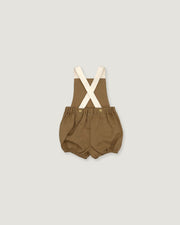 A baby romper in a warm brownish-olive fabric with cream-colored suspenders, laid flat against a light gray background.