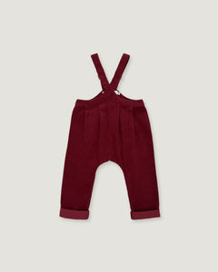 A pair of toddler's burgundy corduroy overall pants with adjustable shoulder straps and rolled cuffs, shown flat on a light gray background.
