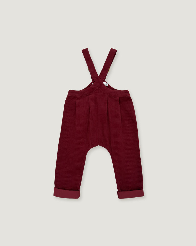 A pair of toddler's burgundy corduroy overall pants with adjustable shoulder straps and rolled cuffs, shown flat on a light gray background.