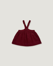 A dark burgundy baby girl's overall dress with adjustable shoulder straps, shown flat against a light gray background.