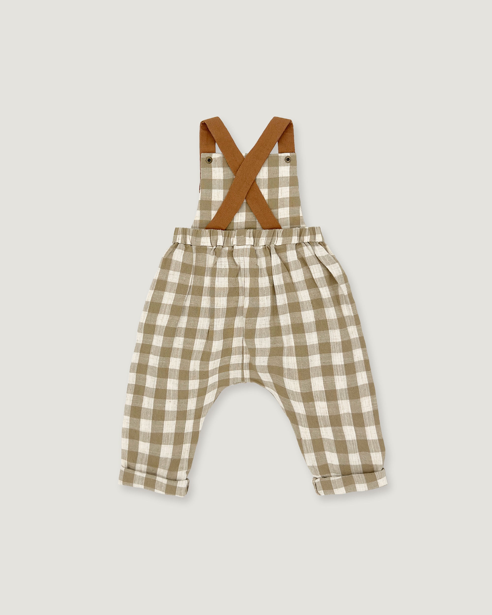 A baby romper with brown suspenders featuring a beige and white gingham check pattern, laid flat on a light gray background.