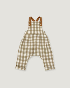 A baby romper in a beige and white gingham check pattern with brown shoulder straps, displayed flat against a light gray background.