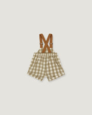 A pair of toddler boy's shorts in a beige and white gingham check pattern, featuring brown adjustable suspenders with metal clasps, laid flat on a light gray background.