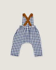 A baby romper with a blue and white gingham check pattern, featuring brown suspenders with a crossed 'X' design at the shoulders, laid flat on a light gray background.