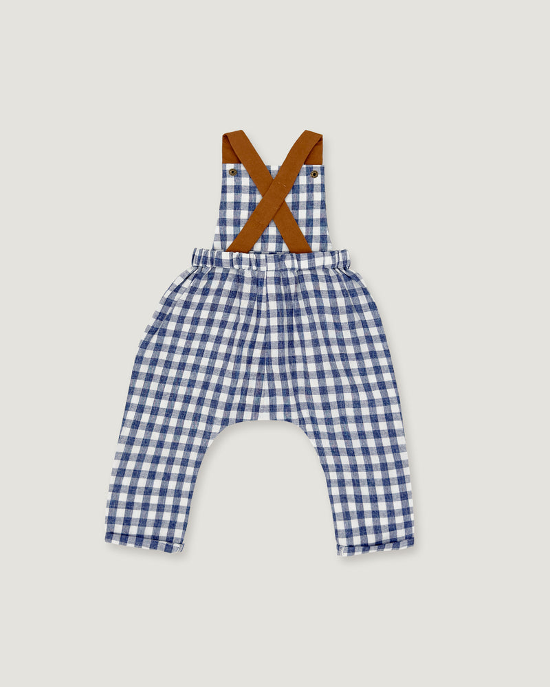 A baby romper with a blue and white gingham check pattern, featuring brown suspenders with a crossed 'X' design at the shoulders, laid flat on a light gray background.
