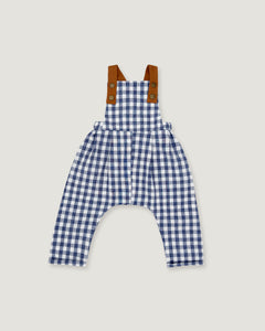 A baby romper in a blue and white gingham pattern with brown shoulder straps, displayed flat against a light gray background.