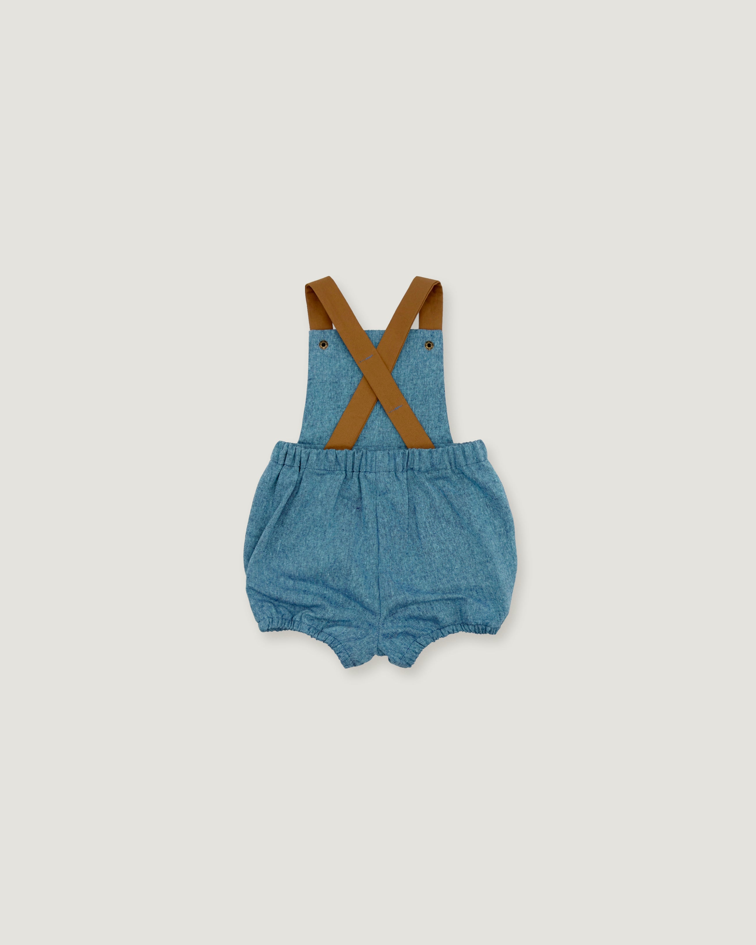 A pair of baby denim bubble shorts with brown suspenders, laid flat on a light gray background.
