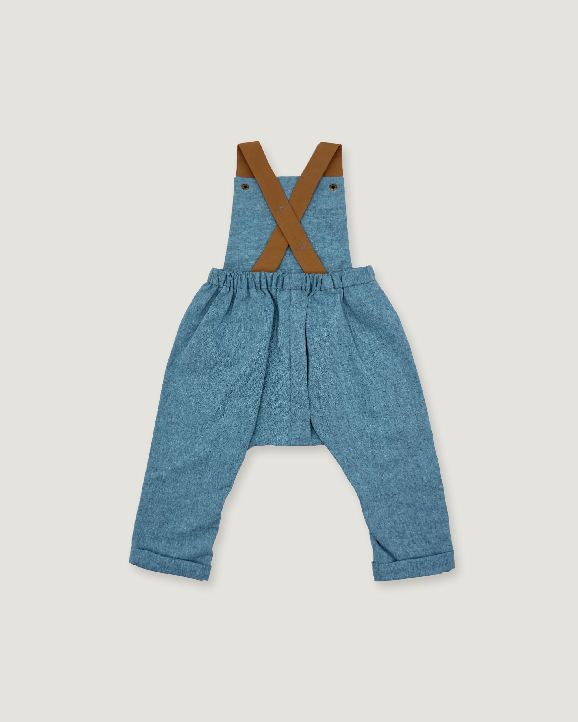 A pair of toddler's blue denim overall-style pants with brown suspenders, laid flat on a light gray background.
