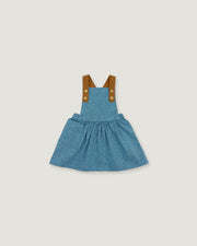 A toddler girl's blue denim overall dress with brown fabric shoulder straps and gold-tone buttons, shown flat on a light gray background.