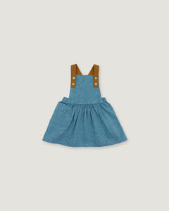 A toddler girl's blue denim overall dress with brown fabric shoulder straps and gold-tone buttons, shown flat on a light gray background.
