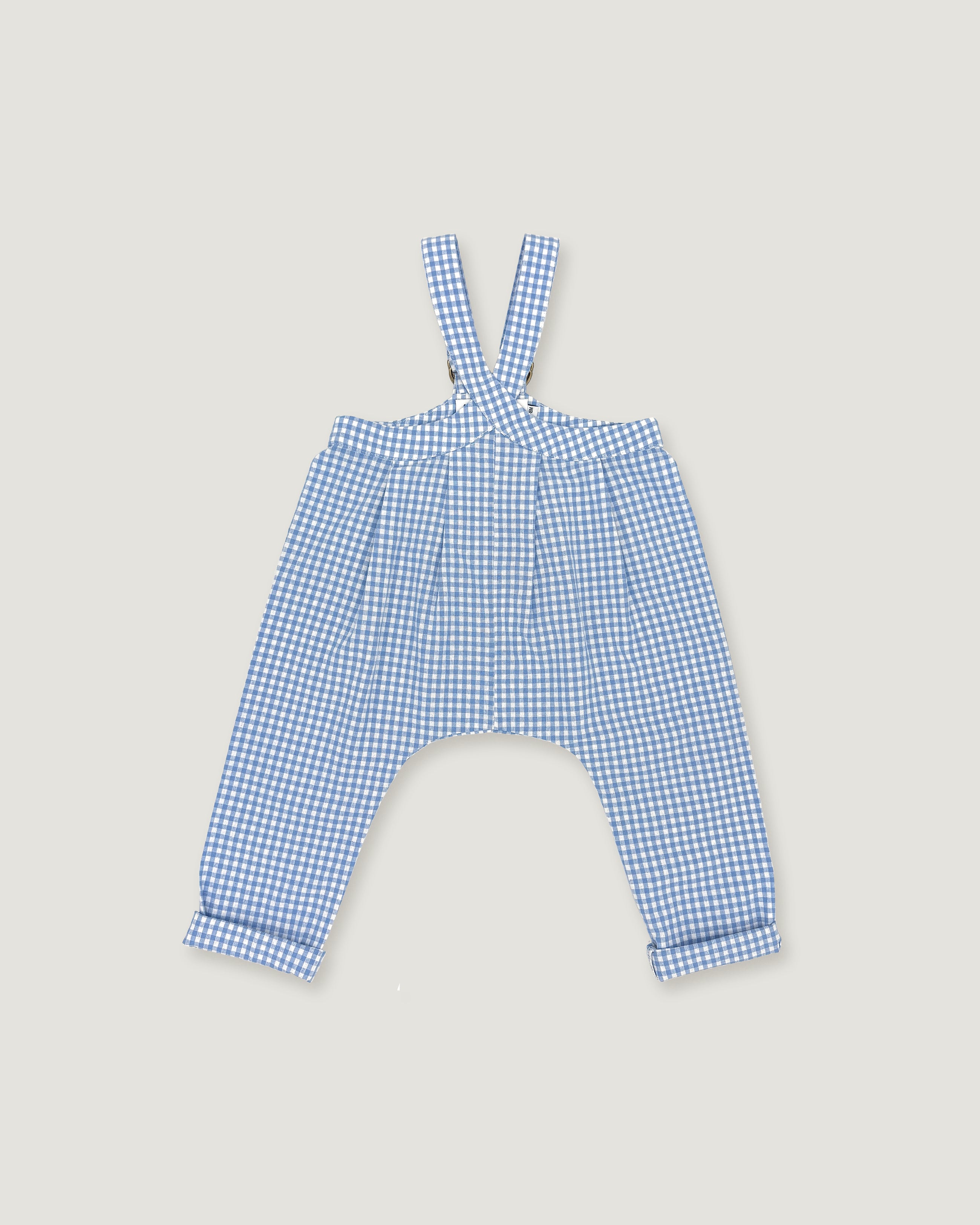 A pair of children's blue and white gingham suspenders with a high waist and wide legs, laid flat on a light beige background.