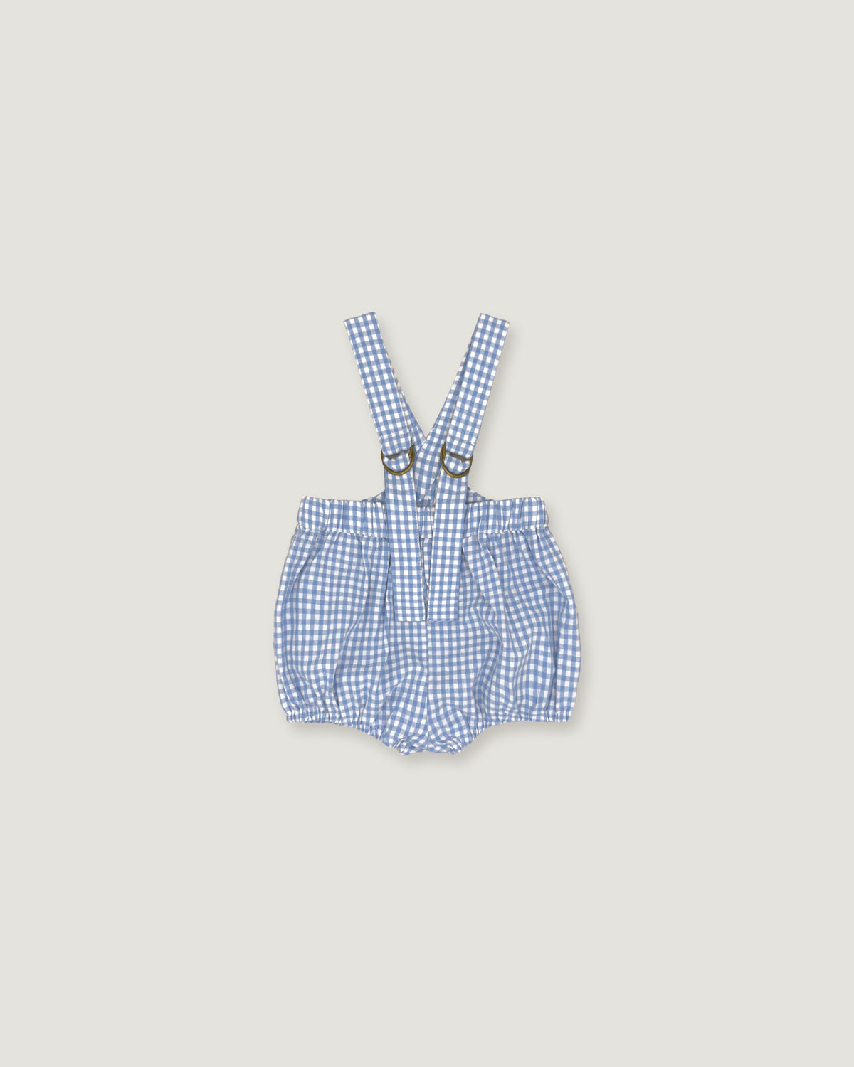 A baby romper with suspenders in a blue and white gingham check pattern, featuring adjustable shoulder straps with metal rings, laid flat on a light beige background.