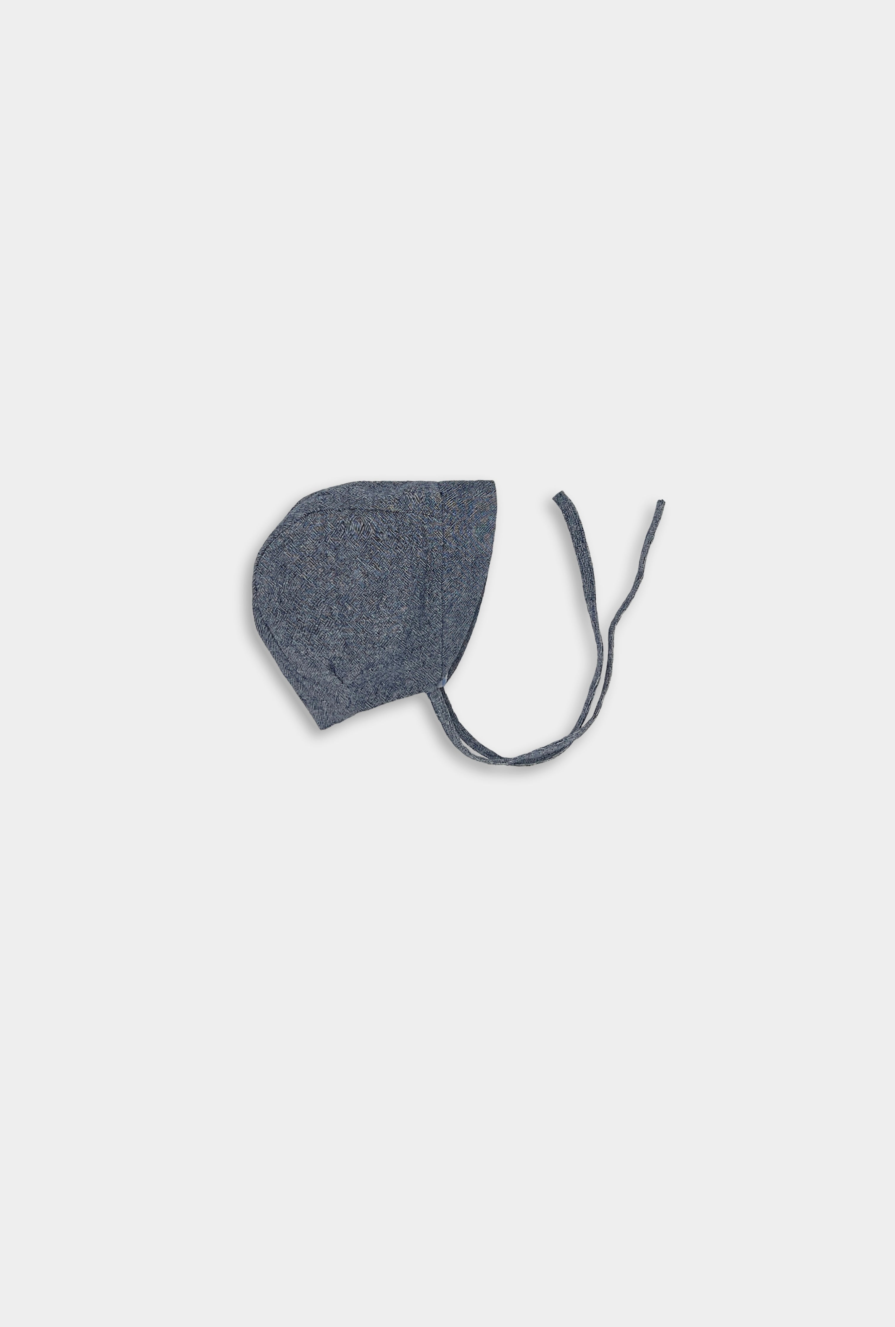 Product Image of Blue Chambray Bonnet: A detailed view of the Blue Chambray bonnet, highlighting its classic design, soft linen fabric, and adjustable pleats, perfect for keeping little heads cool and protected during summer.