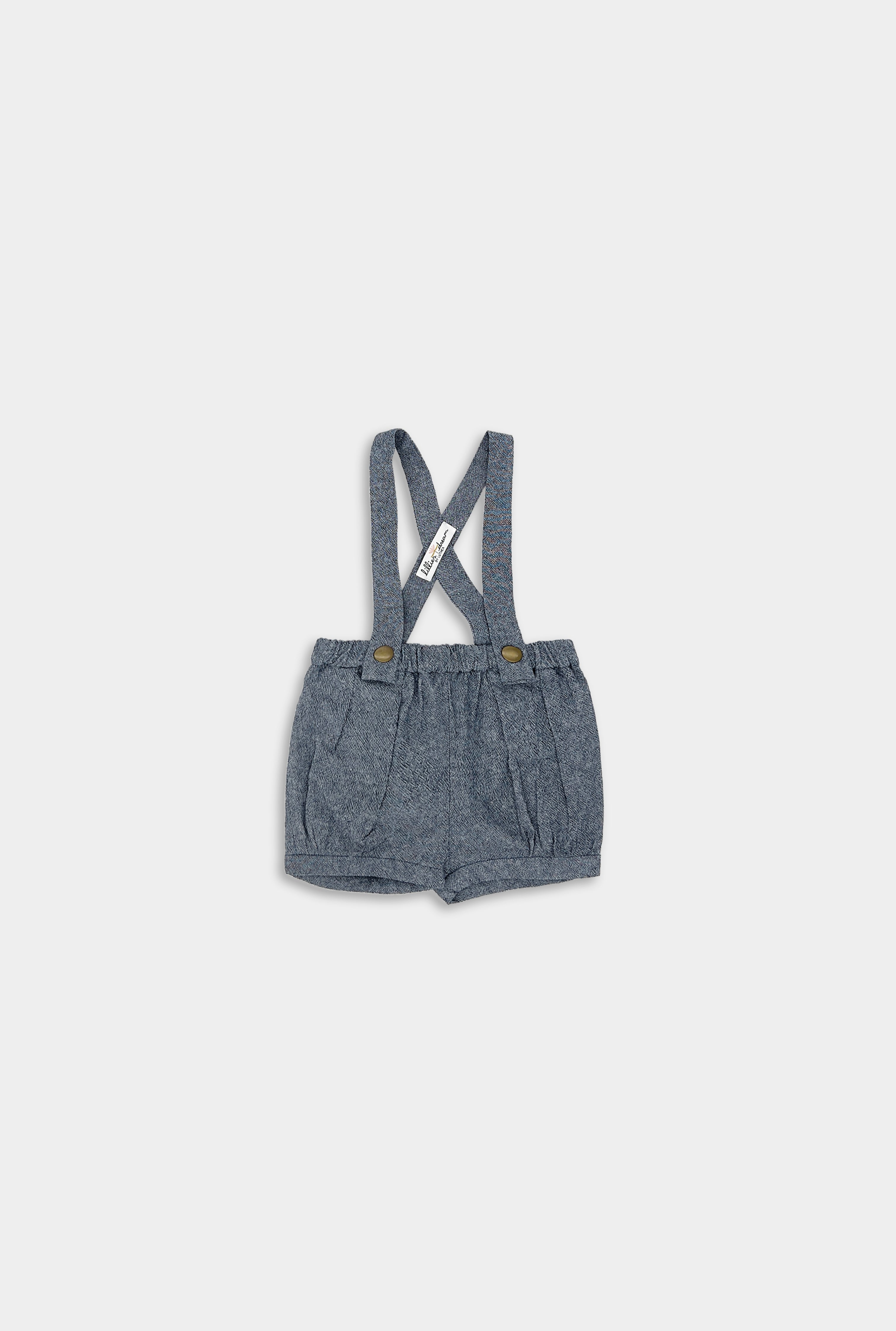Front view of chambray blue linen suspender shorts, featuring adjustable straps, pleats, and cuffs for a stylish and sophisticated look in children’s wear.