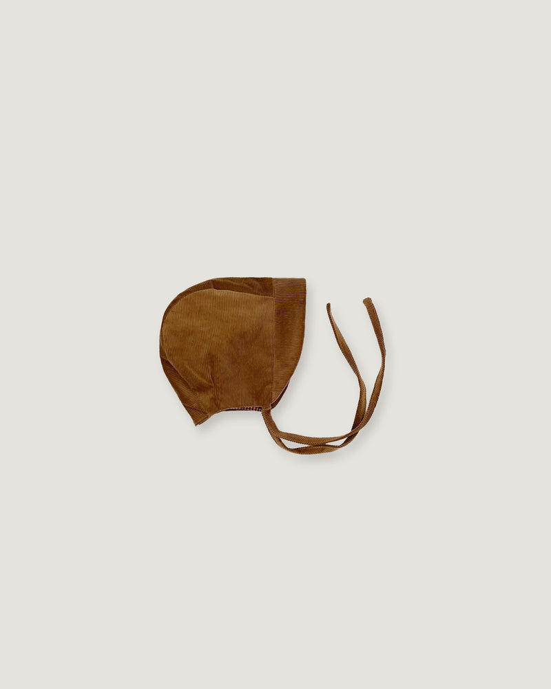 A brown corduroy bonnet with adjustable tie straps, photographed flat against a light gray background.