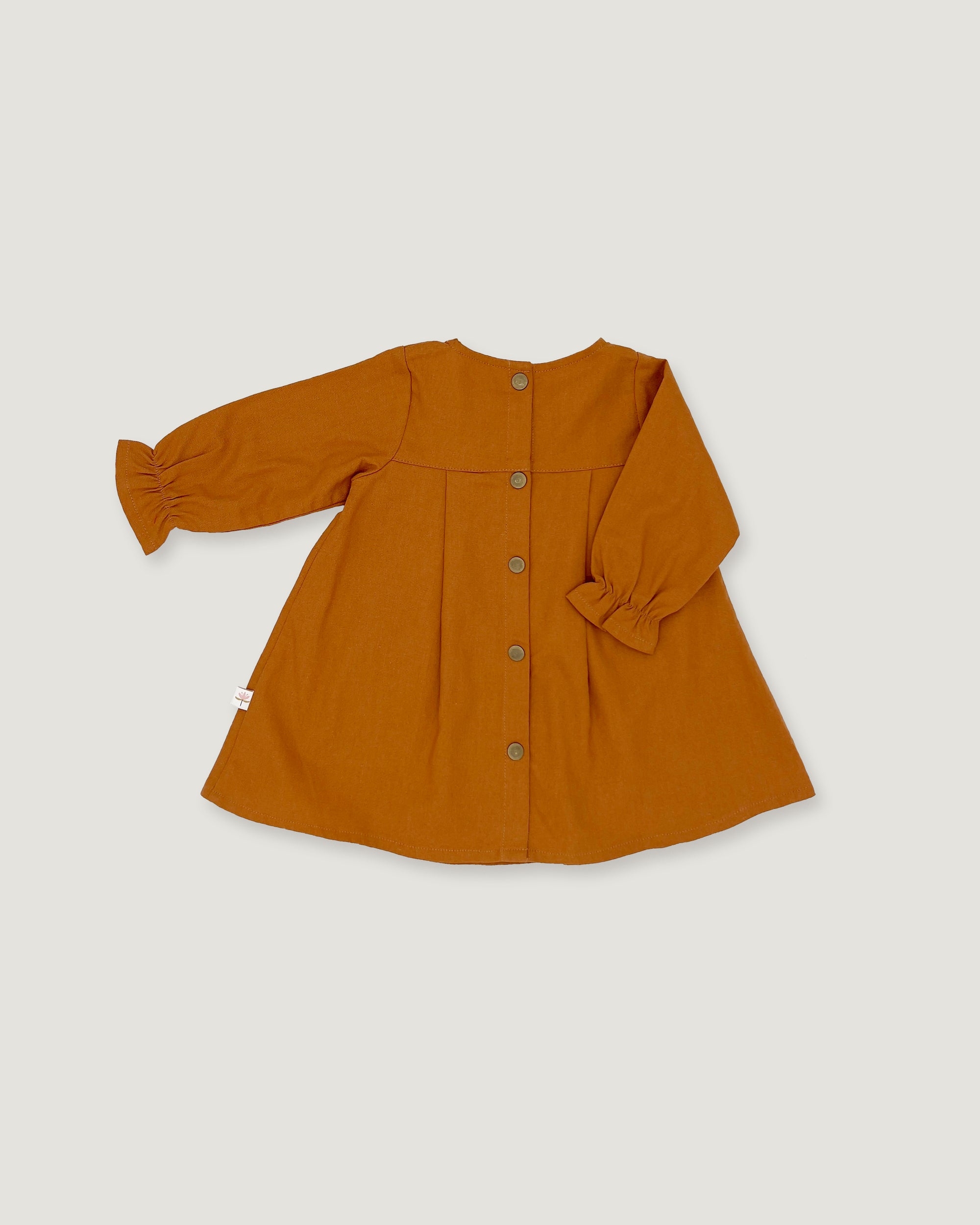 A mustard yellow long-sleeve linen dress for toddlers, featuring a button-down front and gathered sleeves, laid flat on a light gray background.