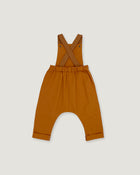 A pair of rust baby overalls with adjustable shoulder straps and a wide leg, laid flat on a light gray background.