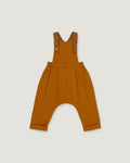 A pair of rust baby overalls with adjustable shoulder straps and a wide leg, laid flat on a light gray background.