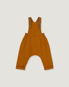 A pair of rust baby overalls with adjustable shoulder straps and a wide leg, laid flat on a light gray background.