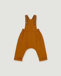 A pair of rust baby overalls with adjustable shoulder straps and a wide leg, laid flat on a light gray background.