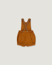 A pair of toddler boy's shortalls in a warm camel brown color, featuring adjustable shoulder straps and a button closure at the waist, displayed flat against a light gray background.