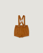 A pair of toddler's pleated shorts in a warm camel brown color, featuring adjustable shoulder straps with a crossed design and a small white brand tag.