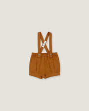 A pair of toddler's pleated shorts in a warm camel brown color, featuring adjustable shoulder straps with a crossed design and a small white brand tag.