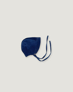 A navy blue corduroy bonnet with long ties, photographed flat on a light gray background.